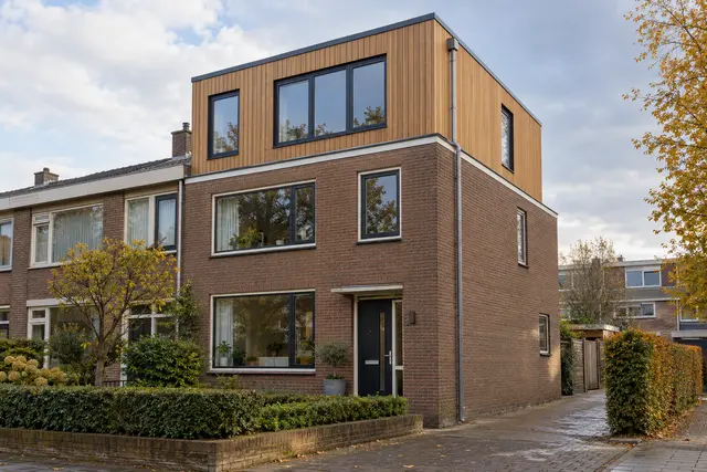 Dakopbouw met houten gevelbekleding op een hoekwoning met plat dak